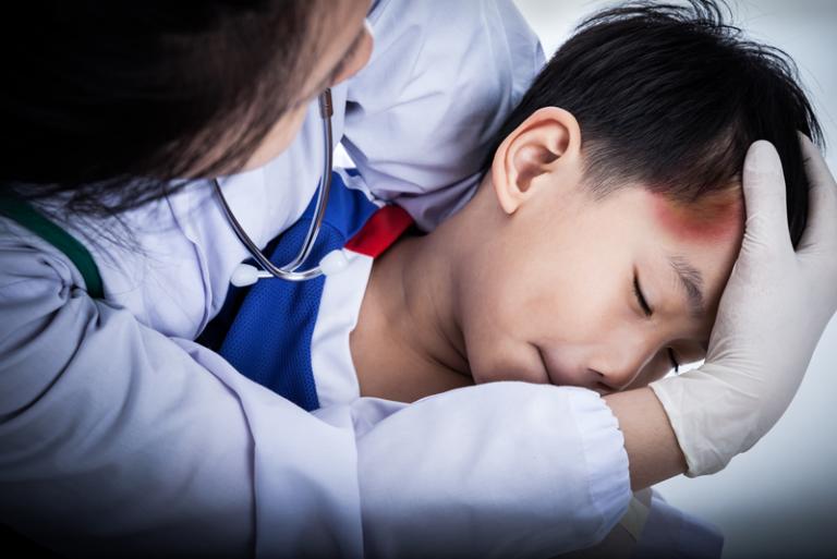 A doctor performs a checkup towards a child with injuries on his forehead