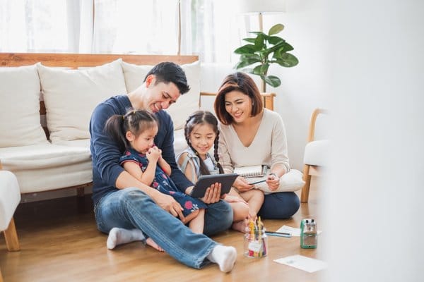 A family sitting in the living room while participating in educational and interactive virtual activities